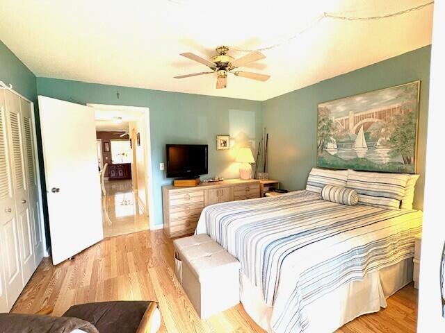 bedroom with ceiling fan, light wood finished floors, and a closet