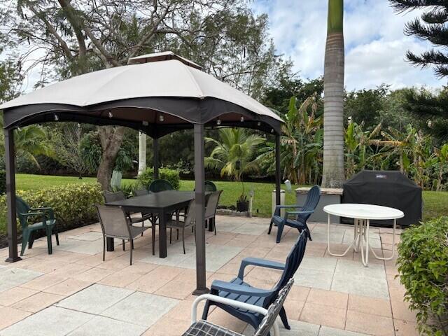 view of patio with outdoor dining space, area for grilling, and a gazebo