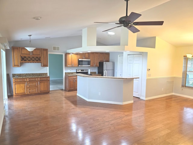 kitchen with appliances with stainless steel finishes, decorative light fixtures, a center island, and hardwood / wood-style flooring