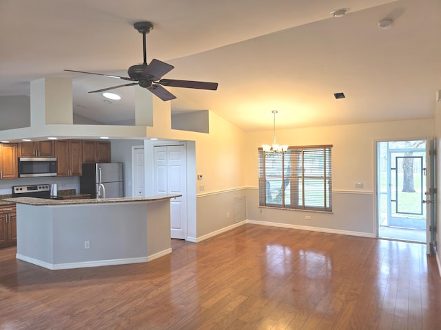 kitchen with appliances with stainless steel finishes, pendant lighting, dark hardwood / wood-style floors, ceiling fan with notable chandelier, and an island with sink