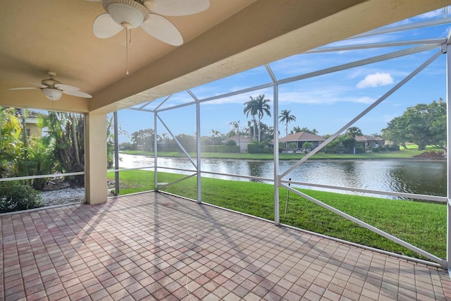 unfurnished sunroom featuring ceiling fan, a water view, and a wealth of natural light