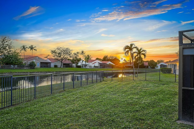 view of yard with a residential view, a water view, and a fenced backyard