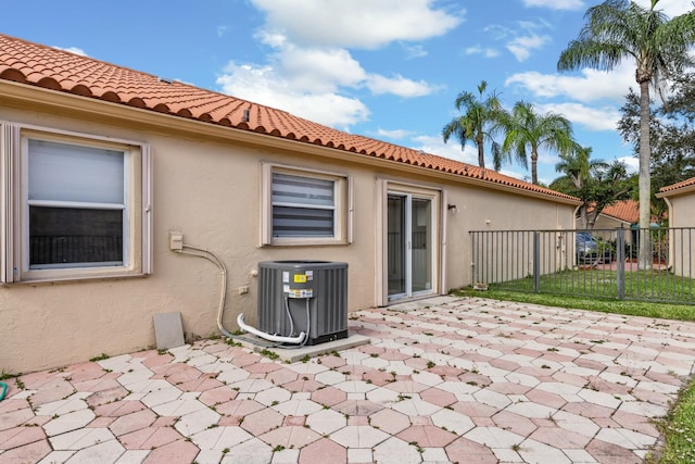 back of property featuring central AC, a patio area, fence, and stucco siding