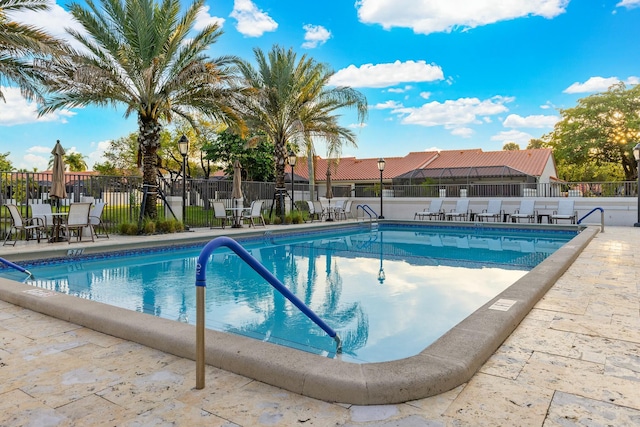 community pool with a patio area and fence