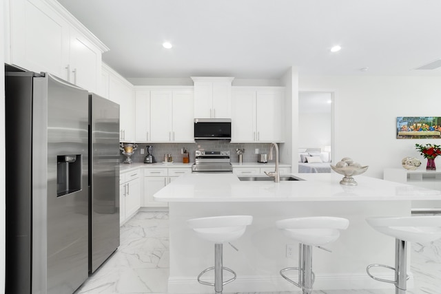 kitchen featuring sink, a center island with sink, appliances with stainless steel finishes, and white cabinetry