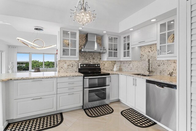 875 E Camino Real Unit 7E, Boca Raton, FL 33432 - kitchen featuring stainless steel appliances, white cabinetry, hanging light fixtures, and wall chimney range hood