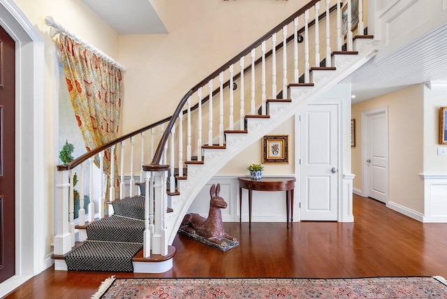 stairway with a towering ceiling, baseboards, and wood finished floors