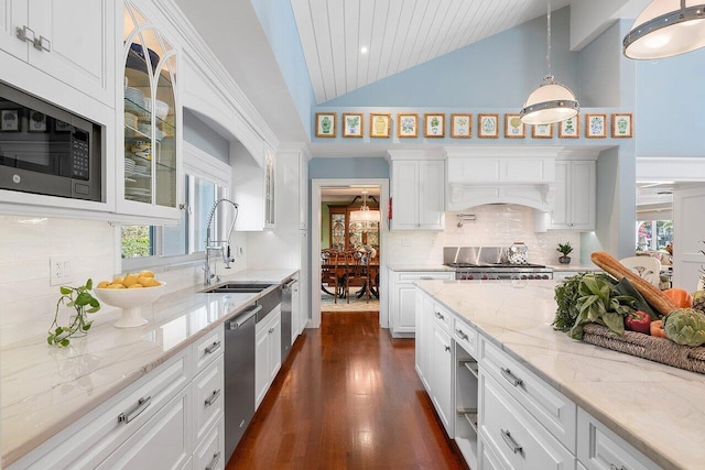 kitchen featuring hanging light fixtures, glass insert cabinets, lofted ceiling, stainless steel appliances, and white cabinets