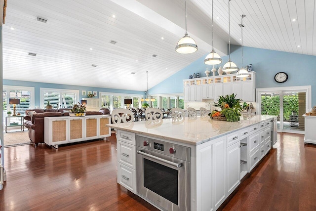 kitchen featuring stainless steel oven, open floor plan, decorative light fixtures, white cabinetry, and a spacious island