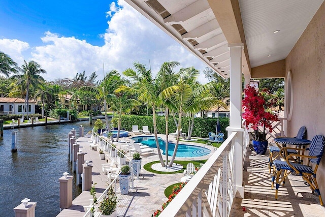 balcony featuring a patio area, a water view, and a pool with connected hot tub