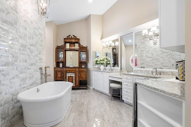 bathroom with vanity, tile walls, a soaking tub, and a notable chandelier