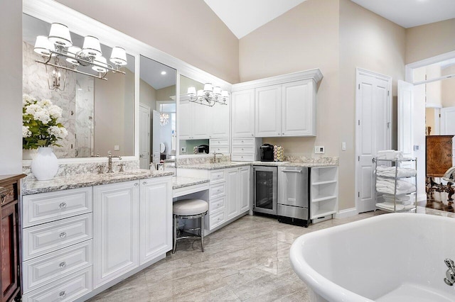 bathroom featuring a soaking tub, beverage cooler, a chandelier, double vanity, and vaulted ceiling