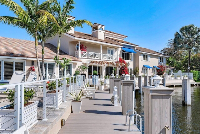 exterior space with a balcony, a water view, and stucco siding