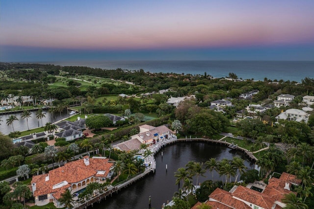 aerial view at dusk featuring a water view and a residential view