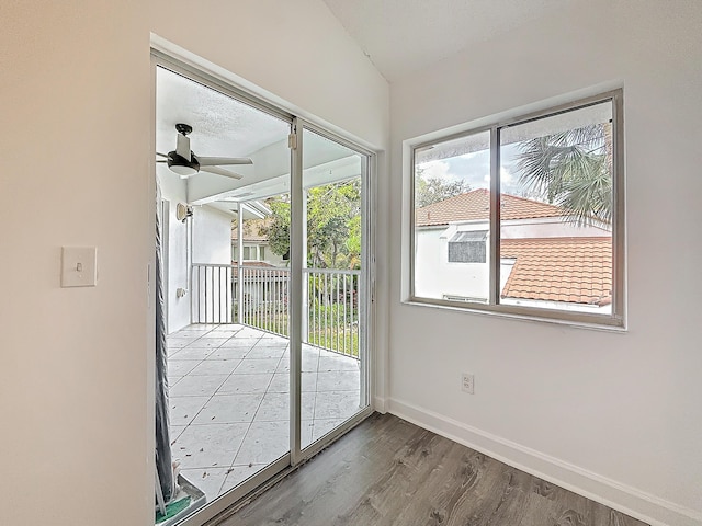 doorway with ceiling fan, wood finished floors, and baseboards