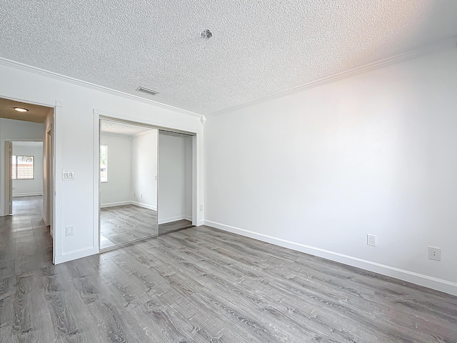 unfurnished bedroom with crown molding, a textured ceiling, and wood finished floors