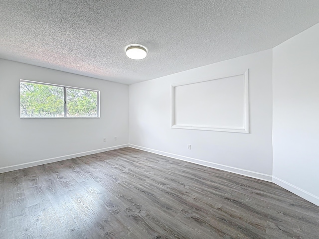 unfurnished room featuring a textured ceiling, baseboards, and wood finished floors