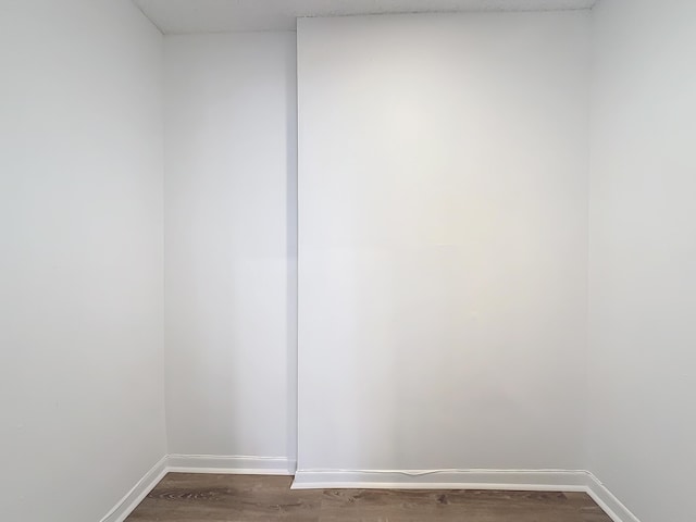 spare room with baseboards and wood finished floors