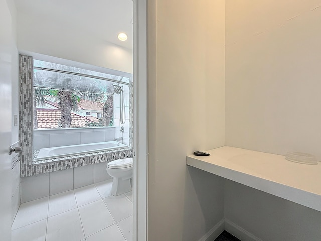 full bathroom with a relaxing tiled tub, toilet, and tile patterned floors