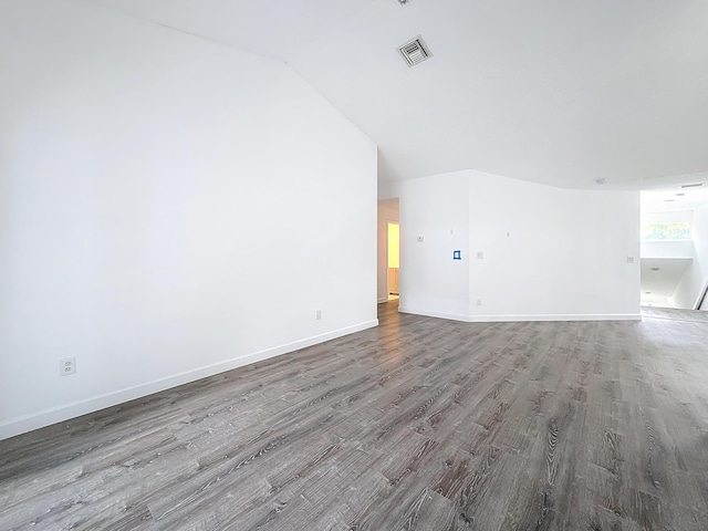 unfurnished living room with lofted ceiling, visible vents, baseboards, and wood finished floors