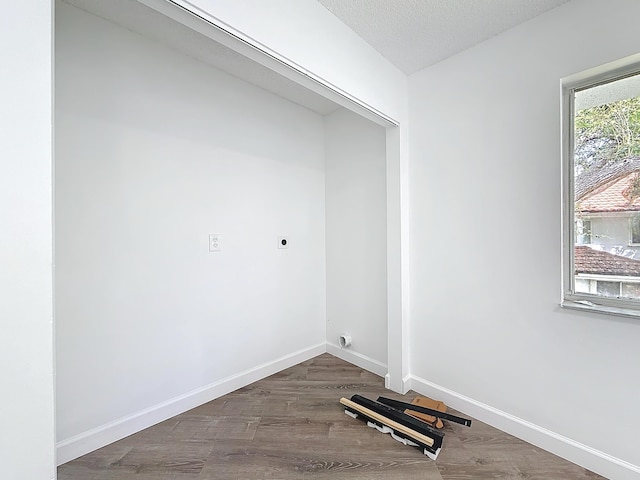 clothes washing area featuring a textured ceiling, hookup for an electric dryer, laundry area, wood finished floors, and baseboards