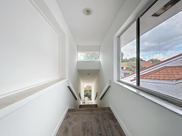 corridor with dark wood-style floors, stairs, and baseboards