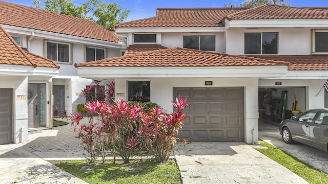 view of front facade with a garage, concrete driveway, a tile roof, and stucco siding