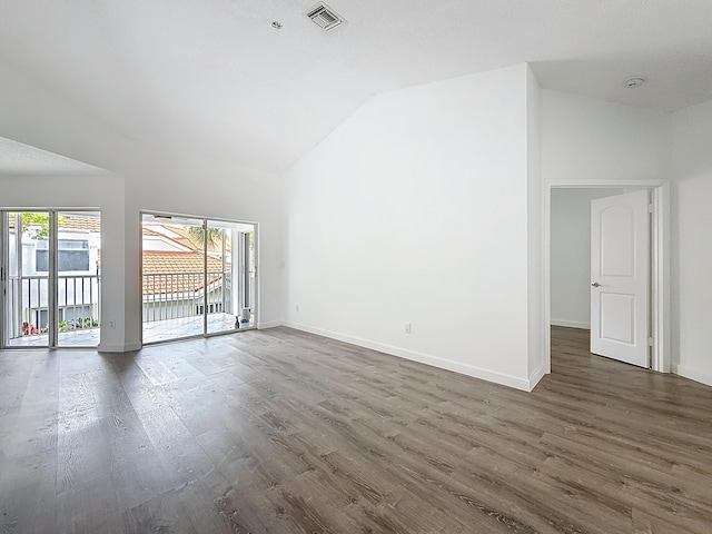 unfurnished room with vaulted ceiling, dark wood-style floors, visible vents, and baseboards