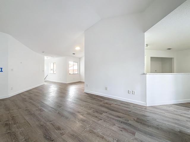 unfurnished living room with dark wood-style floors, lofted ceiling, visible vents, and baseboards