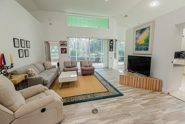 living area with light wood finished floors, baseboards, and high vaulted ceiling