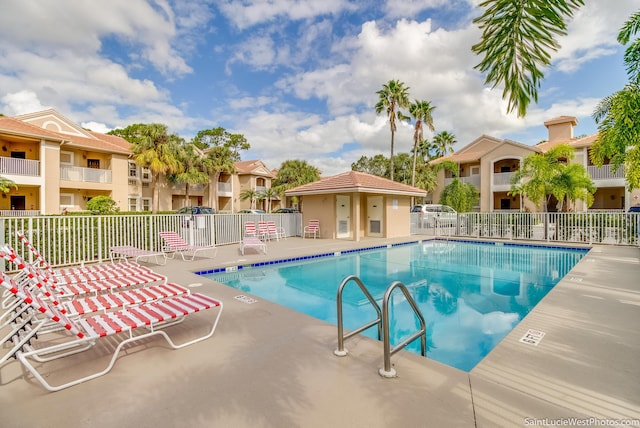 community pool featuring a patio, fence, and a residential view