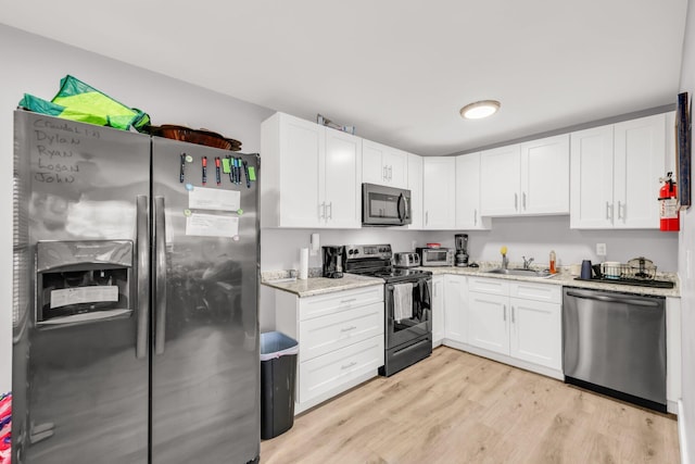 431 SW 1st Ave, Boynton Beach, FL 33435 - kitchen with light stone countertops, light hardwood / wood-style floors, sink, appliances with stainless steel finishes, and white cabinets