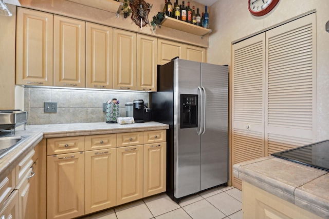 kitchen featuring light tile patterned floors, tile countertops, tasteful backsplash, and stainless steel refrigerator with ice dispenser