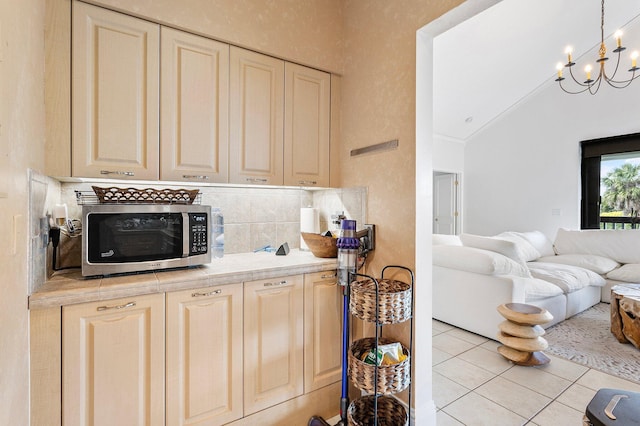 kitchen featuring light tile patterned floors, stainless steel microwave, open floor plan, light countertops, and a chandelier