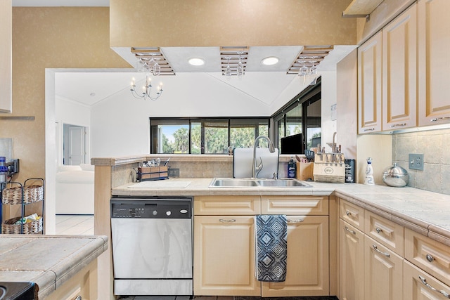 kitchen featuring a peninsula, a sink, stainless steel dishwasher, decorative backsplash, and an inviting chandelier