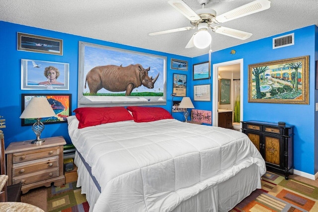 bedroom with a textured ceiling, connected bathroom, and ceiling fan