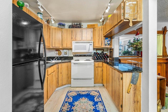 kitchen featuring sink, white appliances, and dark stone countertops