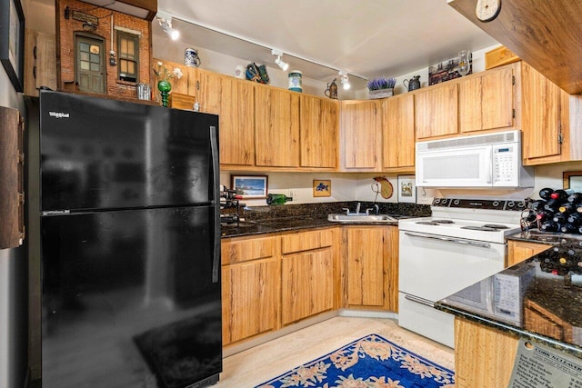 kitchen with white appliances, dark stone countertops, and sink