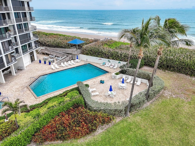 pool featuring a beach view, a water view, and a patio area