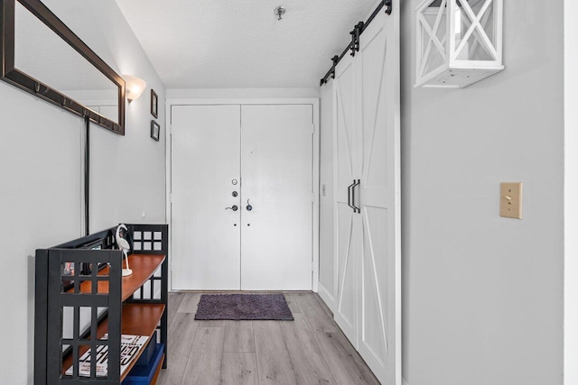 interior space with a textured ceiling, light wood finished floors, and a barn door