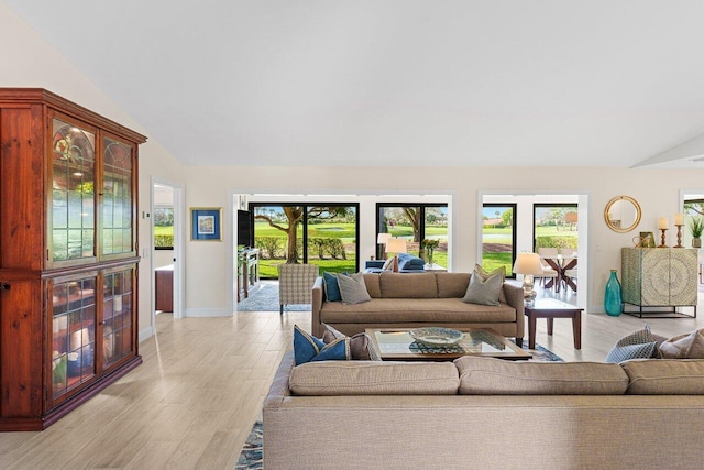 living room featuring a healthy amount of sunlight, vaulted ceiling, and light wood-style flooring