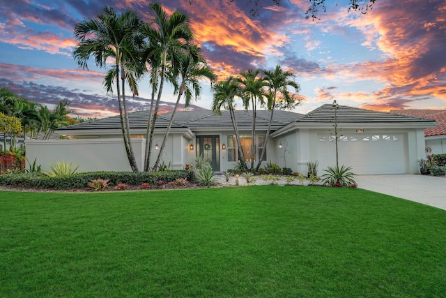 view of front of home with a tiled roof, a front yard, stucco siding, driveway, and an attached garage