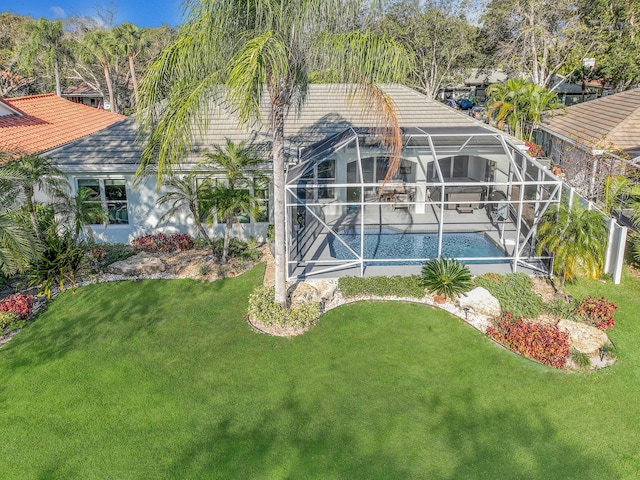 exterior space with a patio, glass enclosure, an outdoor pool, and a lawn