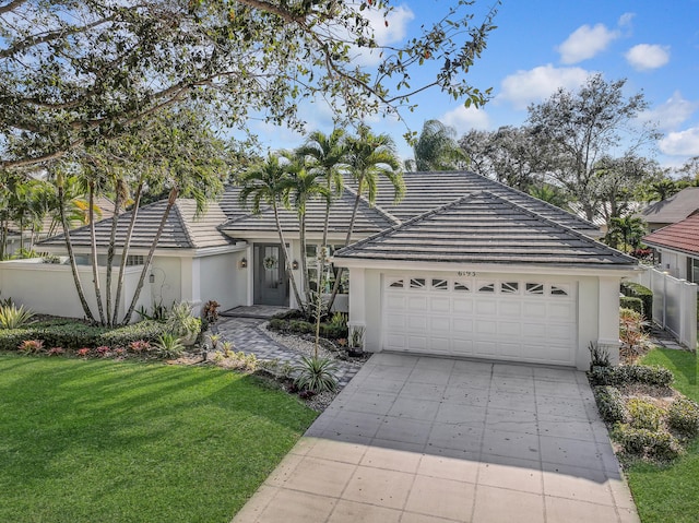 view of front of home with a front lawn, stucco siding, driveway, and a tile roof