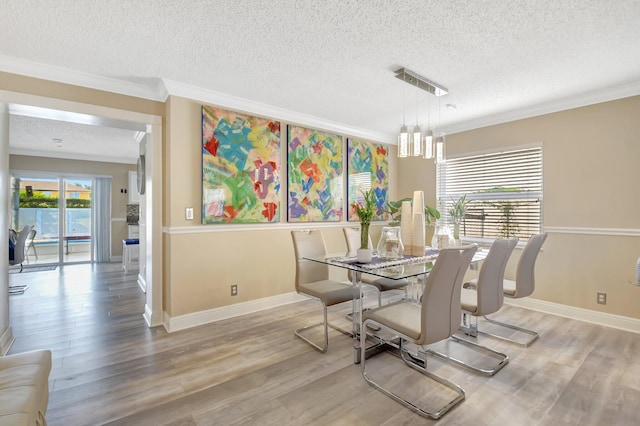 dining area featuring a textured ceiling, light wood-type flooring, and crown molding