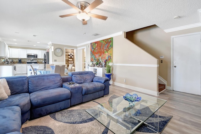 living room with a textured ceiling, light wood-style floors, and crown molding