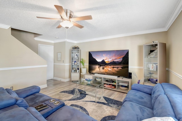 living room with light wood finished floors, baseboards, ceiling fan, crown molding, and a textured ceiling