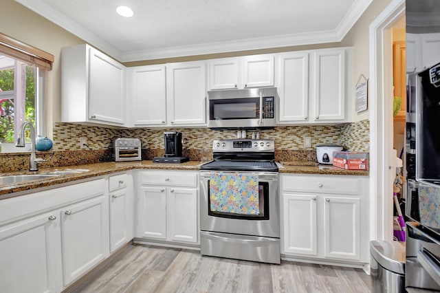 kitchen with stainless steel appliances, white cabinetry, and dark stone countertops