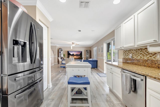 kitchen featuring light stone countertops, white cabinetry, stainless steel appliances, and open floor plan