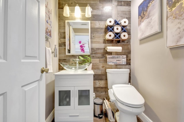 half bath featuring toilet, vanity, and baseboards